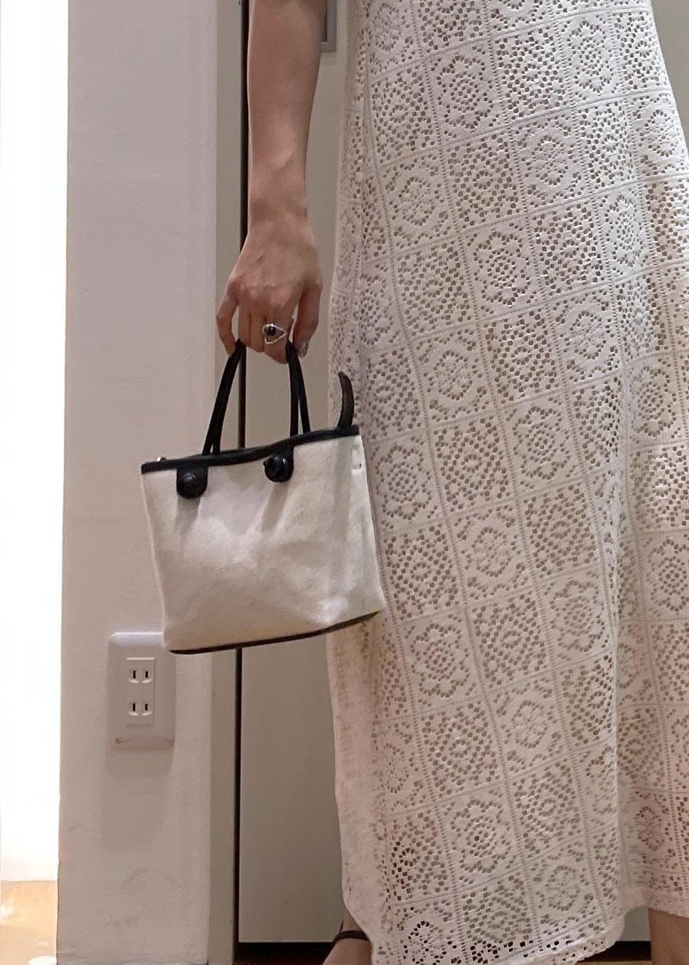 ブラック系のニット/セーター、ブラック系のトートバッグ、ブラック系のサンダルを着用したレディースの夏コーディネートの7枚目の写真