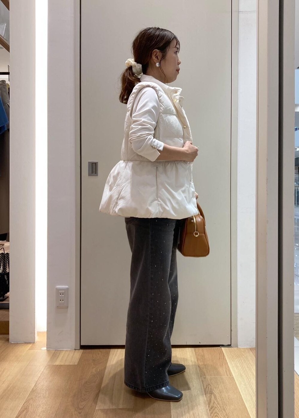 ホワイト系のダウンベスト、ホワイト系のTシャツ/カットソー、グレー系のブーツを着用したレディースの秋コーディネートの3枚目の写真