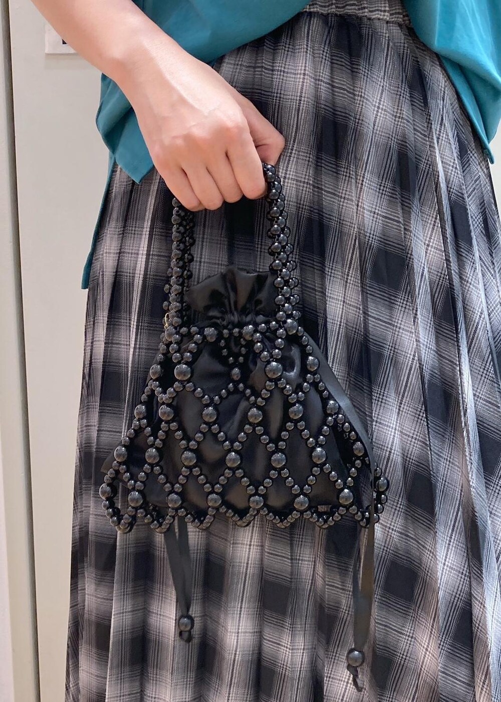 ブラック系のハンドバッグ、ブラック系のバレエシューズ、グリーン系のTシャツ/カットソーを着用したレディースの夏コーディネートの7枚目の写真