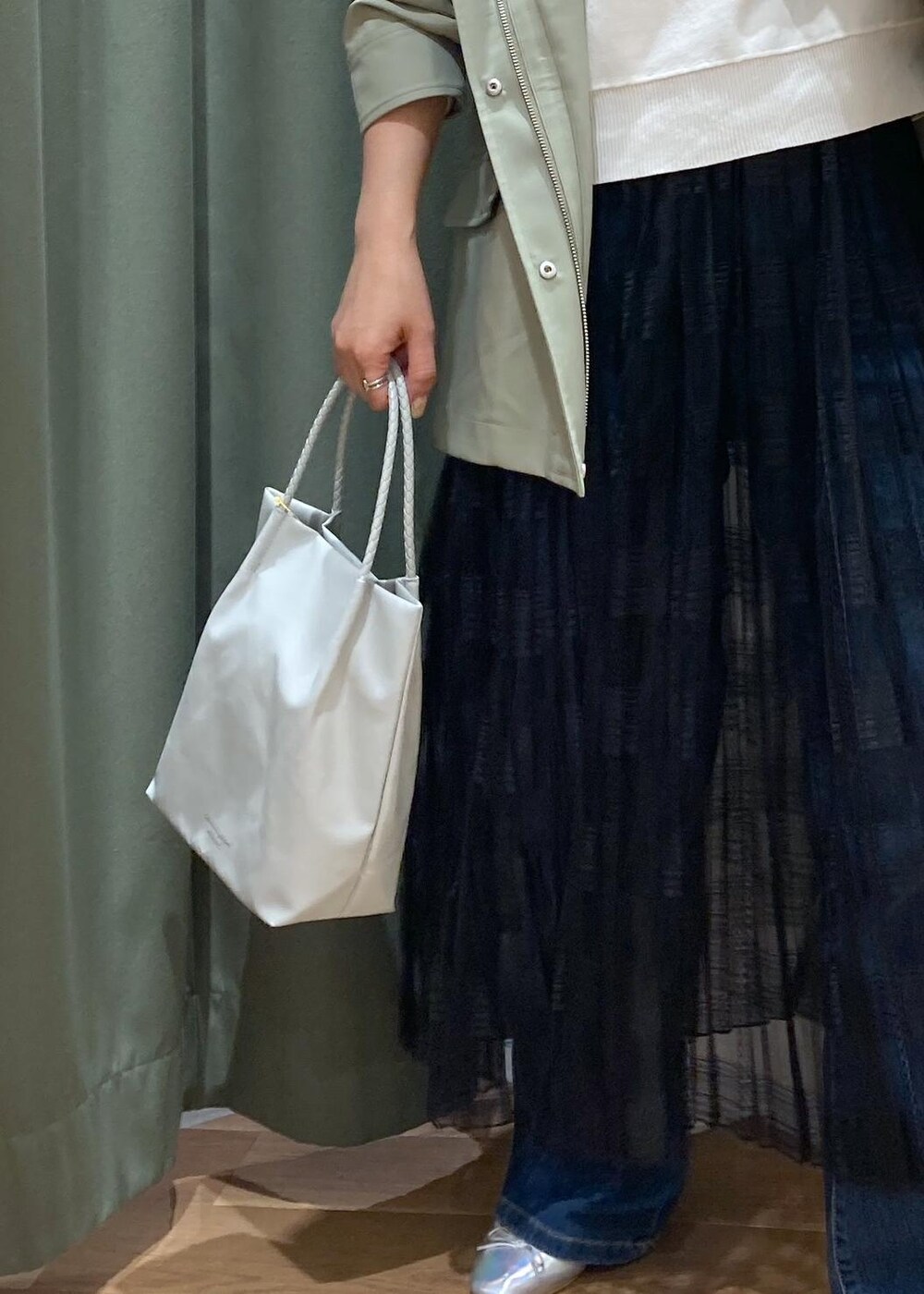 ブルー系のデニムパンツ、ブラック系のスカート、グリーン系のマウンテンパーカーを着用したレディースの春コーディネートの9枚目の写真