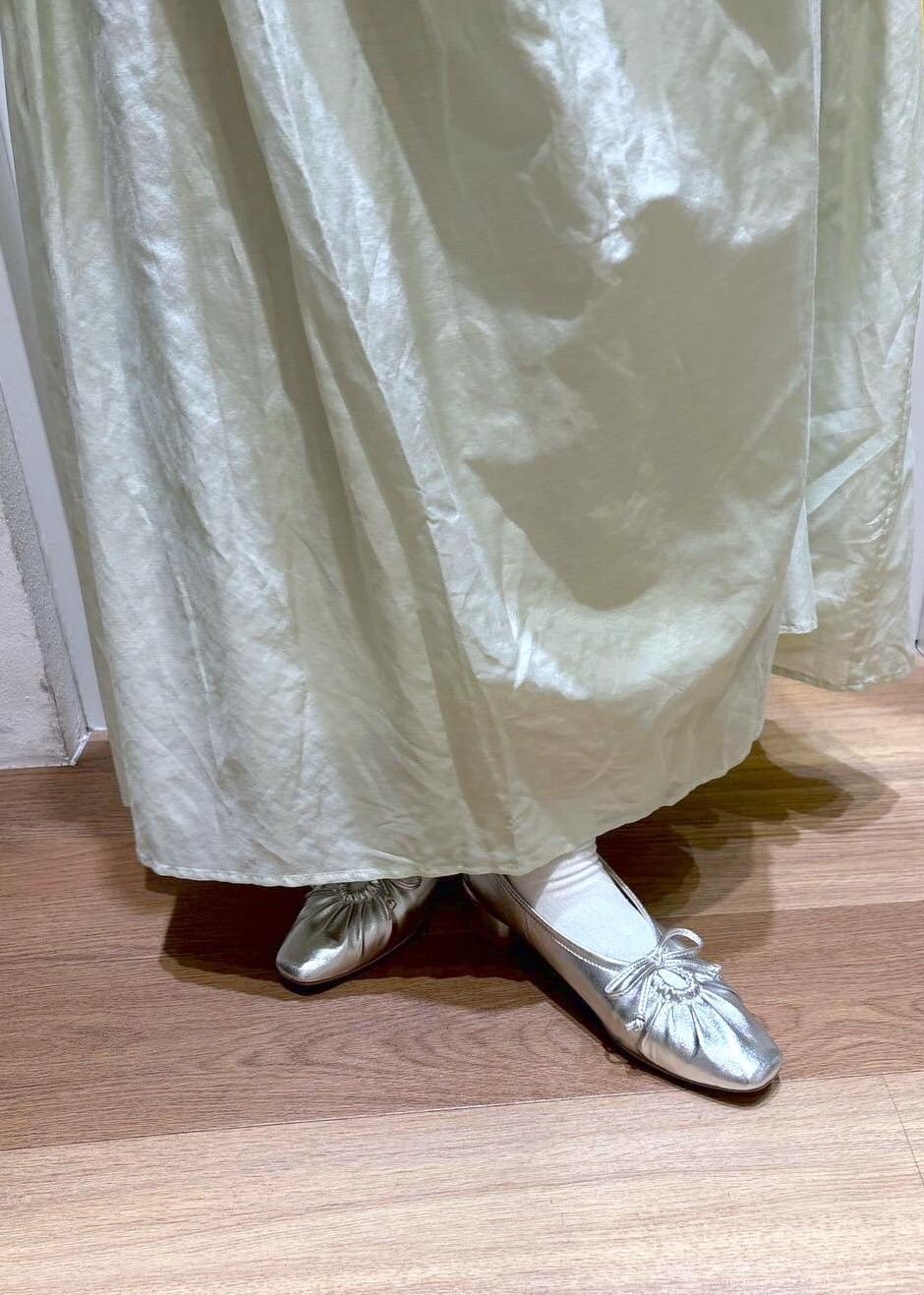 グリーン系のスカート、シルバー系のパンプス、ホワイト系のベストを着用したレディースの春コーディネートの5枚目の写真