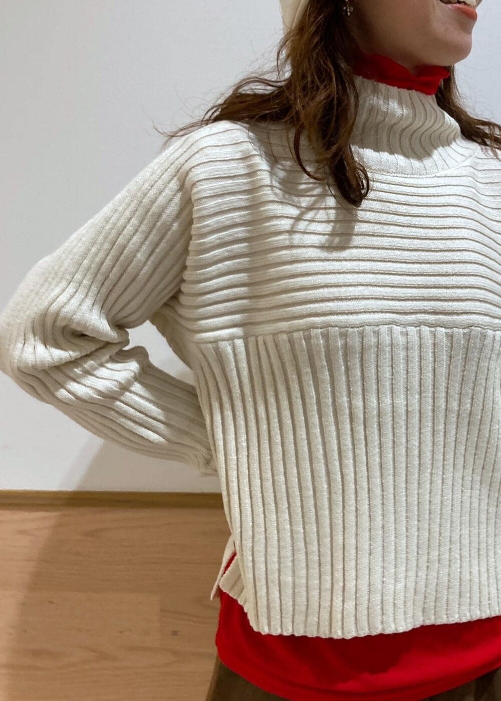 レッド系のTシャツ/カットソー、ホワイト系のニット/セーター、ブラウン系のブーツを着用したレディースの冬コーディネートの2枚目の写真