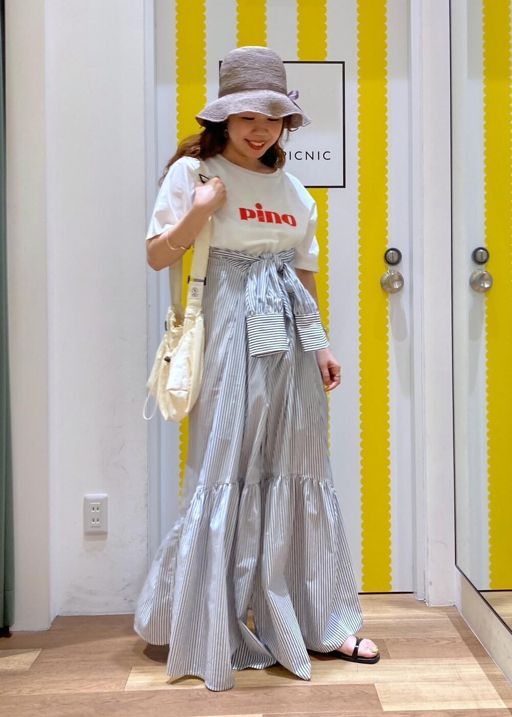 ブラック系のサンダル、ホワイト系のショルダーバッグ、ブルー系のシャツワンピースを着用したレディースの春コーディネートの2枚目の写真