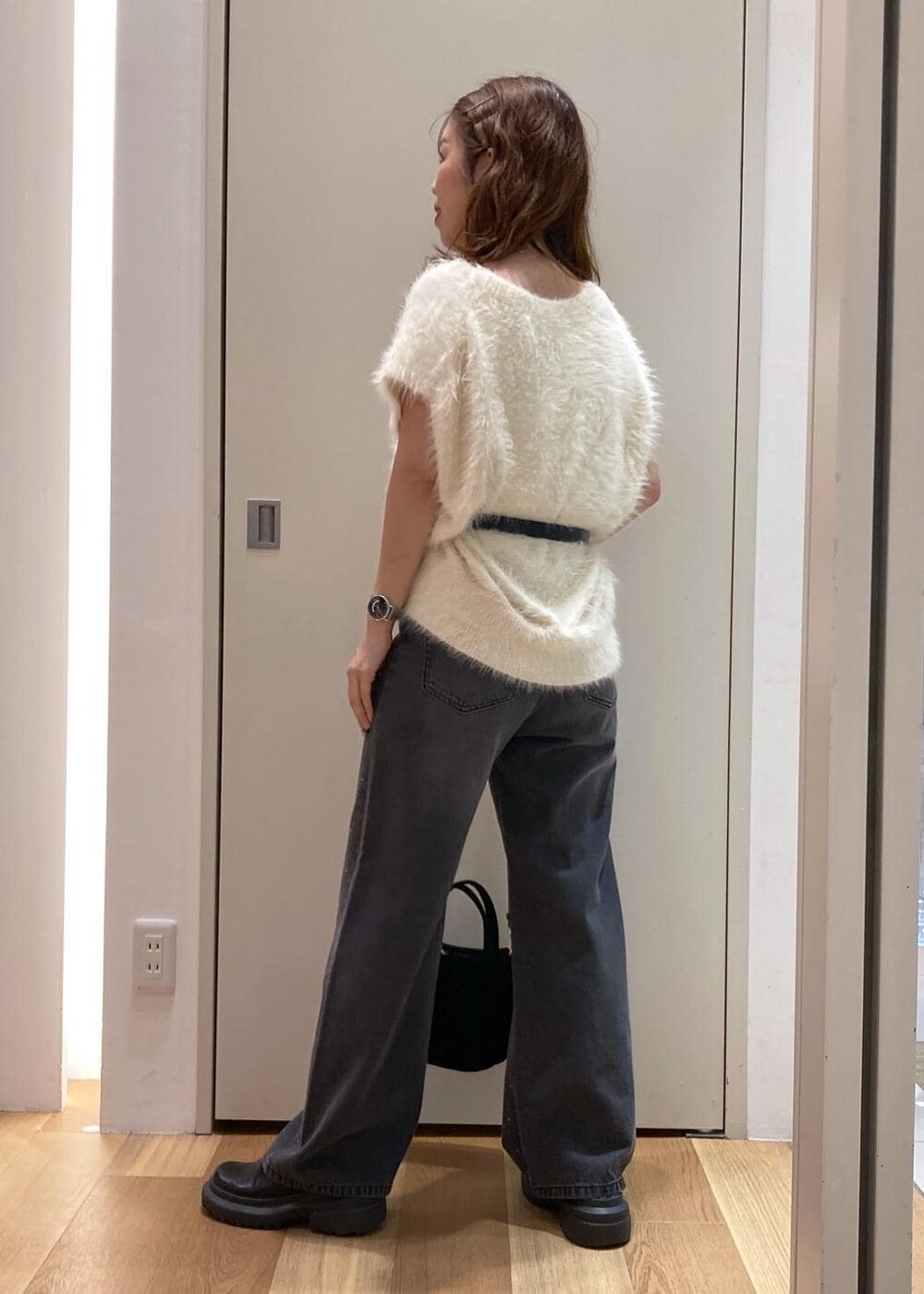 ホワイト系のベスト、ブラック系のデニムパンツ、ブラック系のショルダーバッグを着用したレディースの夏コーディネートの4枚目の写真