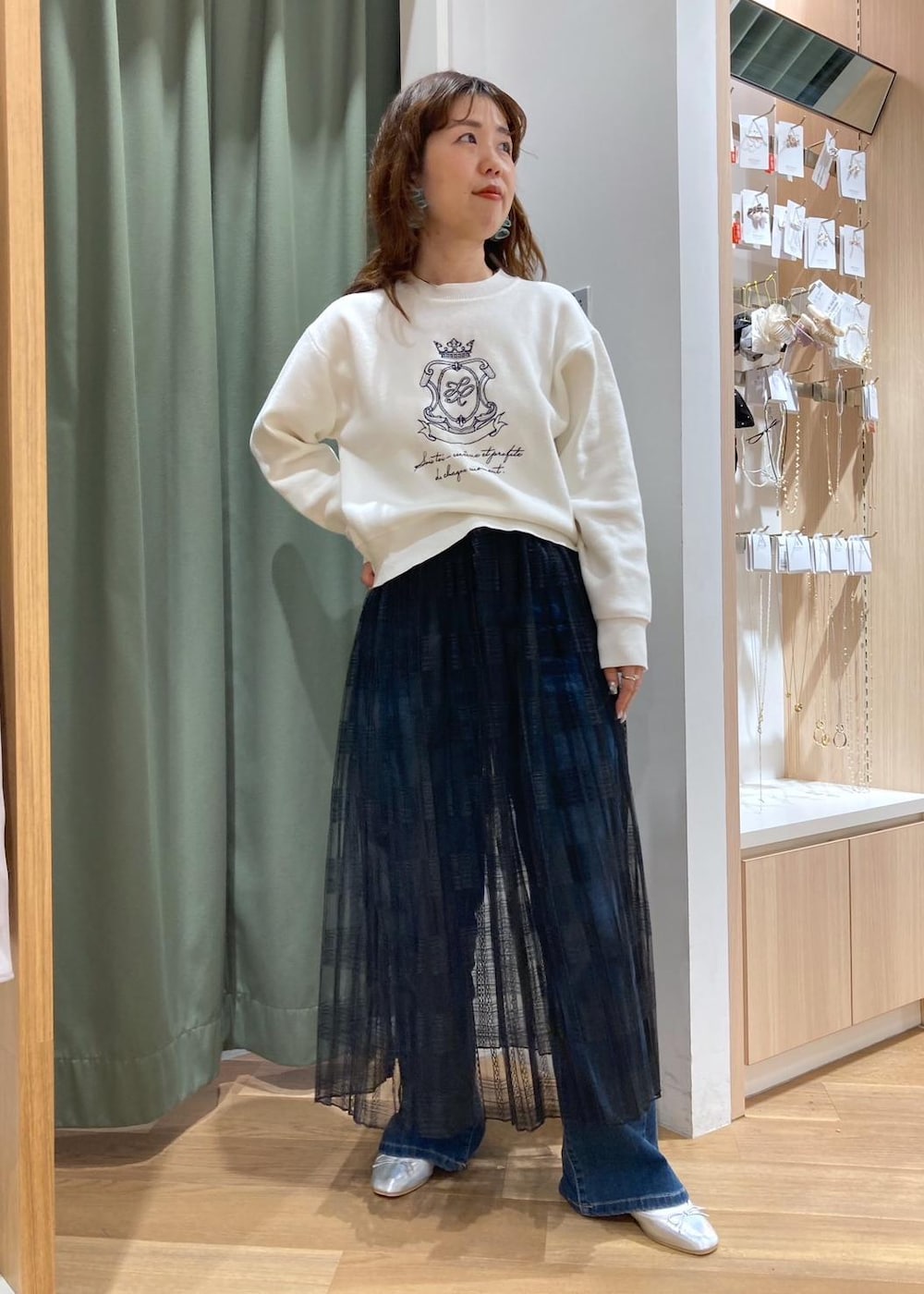 ブルー系のデニムパンツ、ブラック系のスカート、グリーン系のマウンテンパーカーを着用したレディースの春コーディネートの3枚目の写真