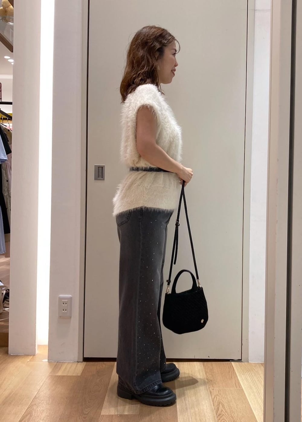 ホワイト系のベスト、ブラック系のデニムパンツ、ブラック系のショルダーバッグを着用したレディースの夏コーディネートの3枚目の写真