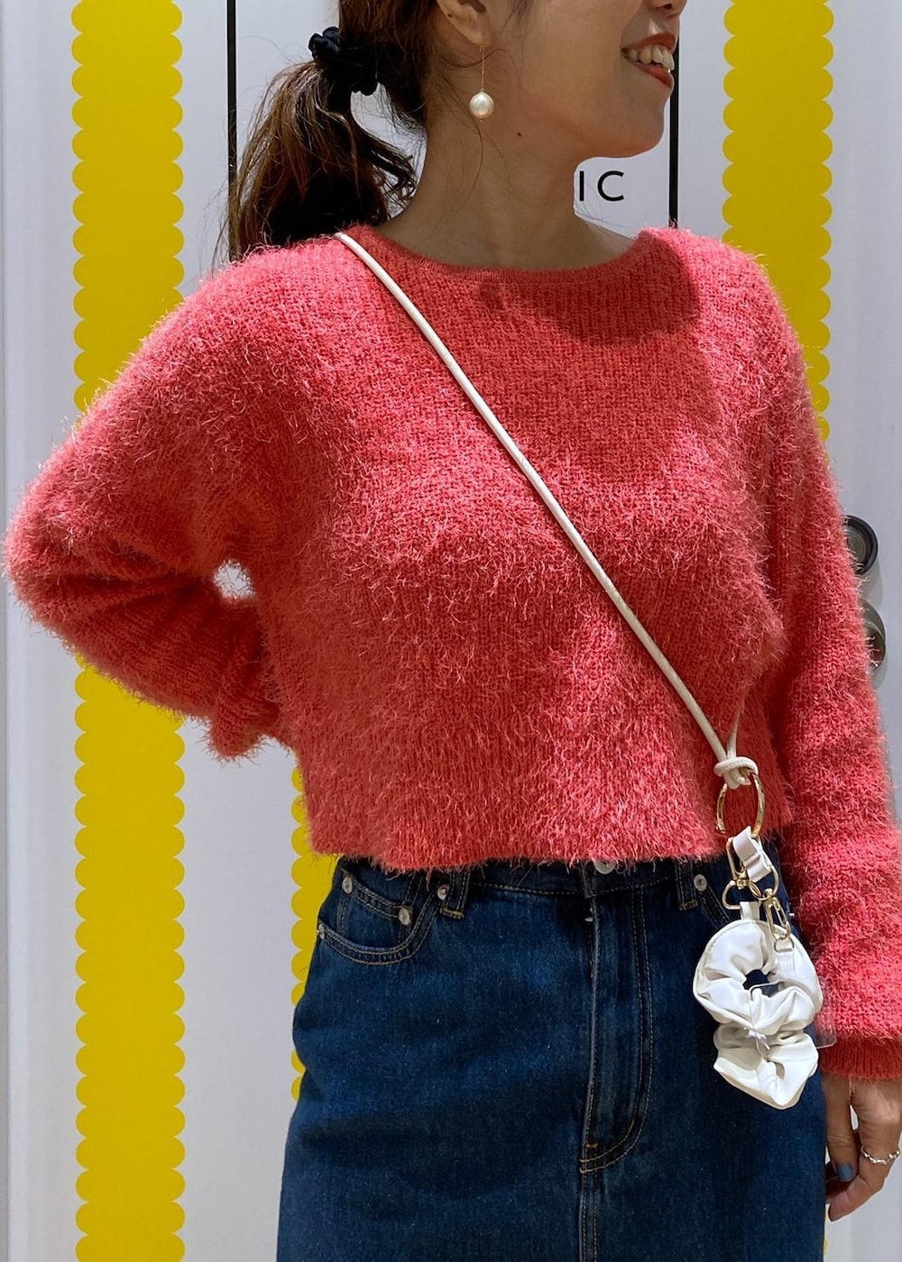 ピンク系のニット/セーター、ブルー系のデニムスカート、ホワイト系のスマホグッズを着用したレディースの冬コーディネートの2枚目の写真