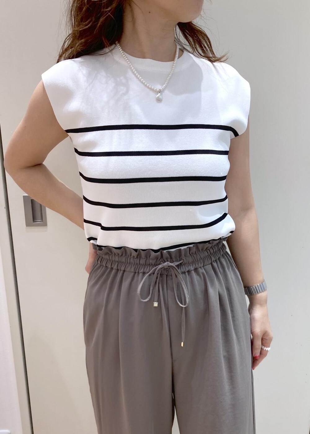 ホワイト系のトートバッグ、ホワイト系のニット/セーター、ベージュ系のTシャツ/カットソーを着用したレディースの夏コーディネートの6枚目の写真