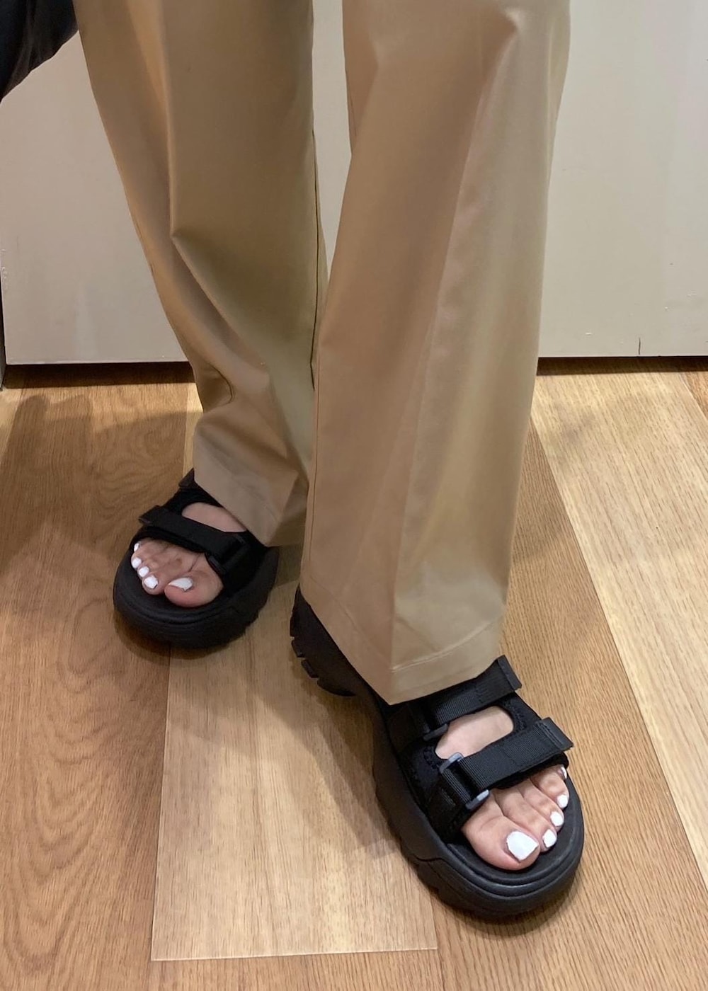 ブラック系のトートバッグ、ブラック系のサンダル、グレー系のチノパンツを着用したレディースの夏コーディネートの7枚目の写真