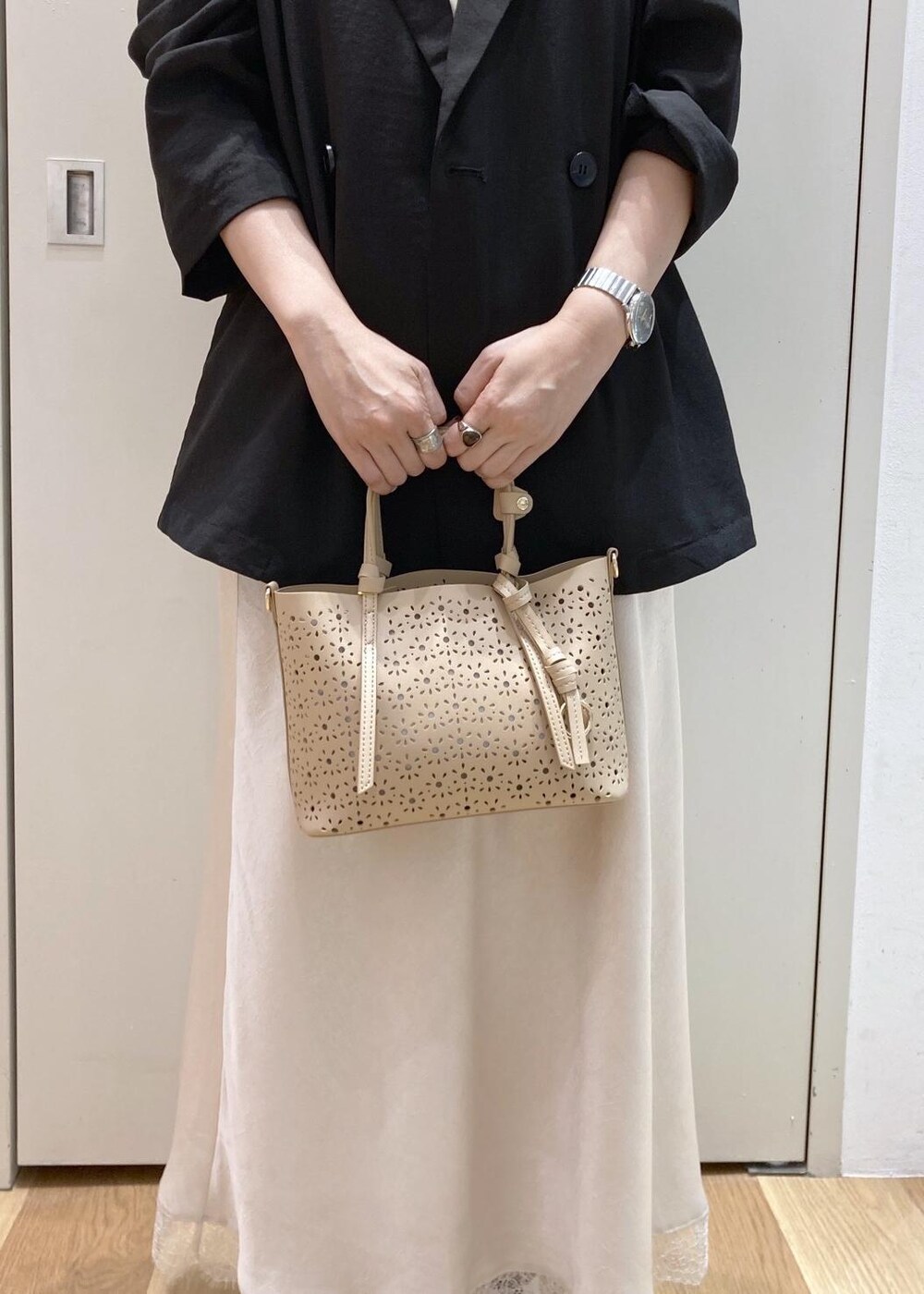 ブラック系のパンプス、ベージュ系のショルダーバッグ、ホワイト系のスカートを着用したレディースの春コーディネートの8枚目の写真