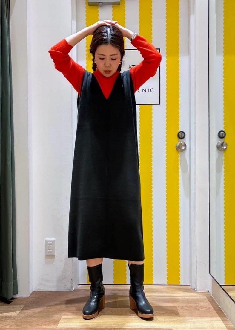 グレー系のジャンパースカート、レッド系のニット/セーター、ブラック系のブーツを着用したレディースの冬コーディネートの2枚目の写真