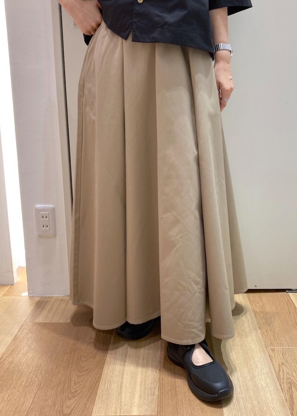 ブラック系のスニーカー、ベージュ系のスカート、ブラック系のシャツ/ブラウスを着用したレディースの夏コーディネートの6枚目の写真