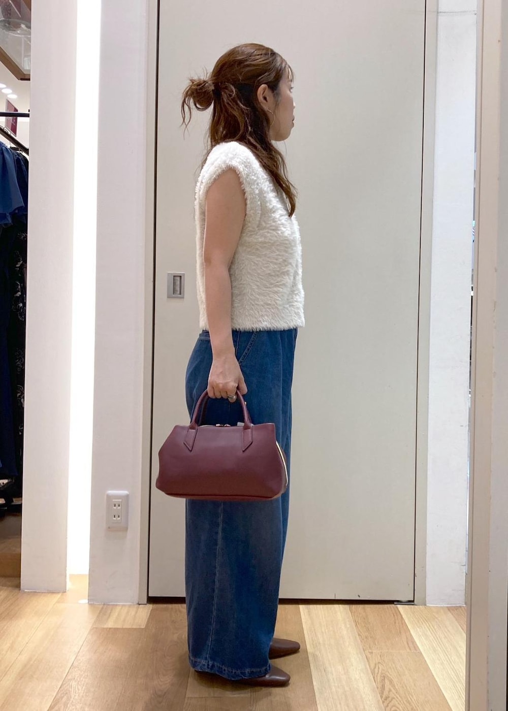 ブラウン系のパンプス、ブルー系のデニムパンツ、レッド系のトートバッグを着用したレディースの夏コーディネートの2枚目の写真