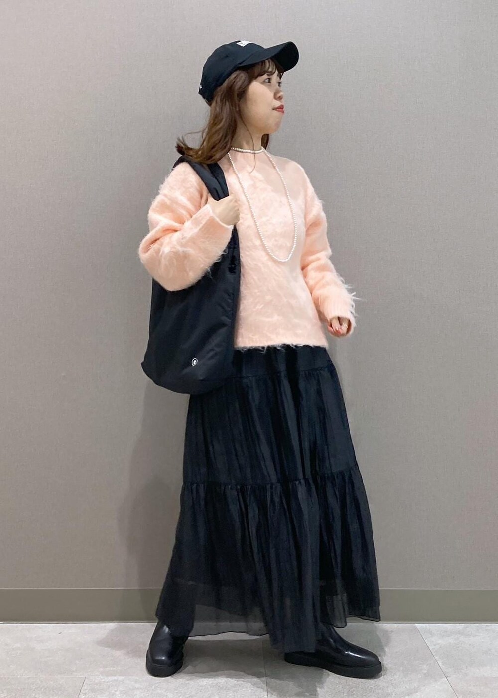 ブラック系のブーツ、ブラック系のトートバッグ、ピンク系のニット/セーターを着用したレディースの冬コーディネートの2枚目の写真