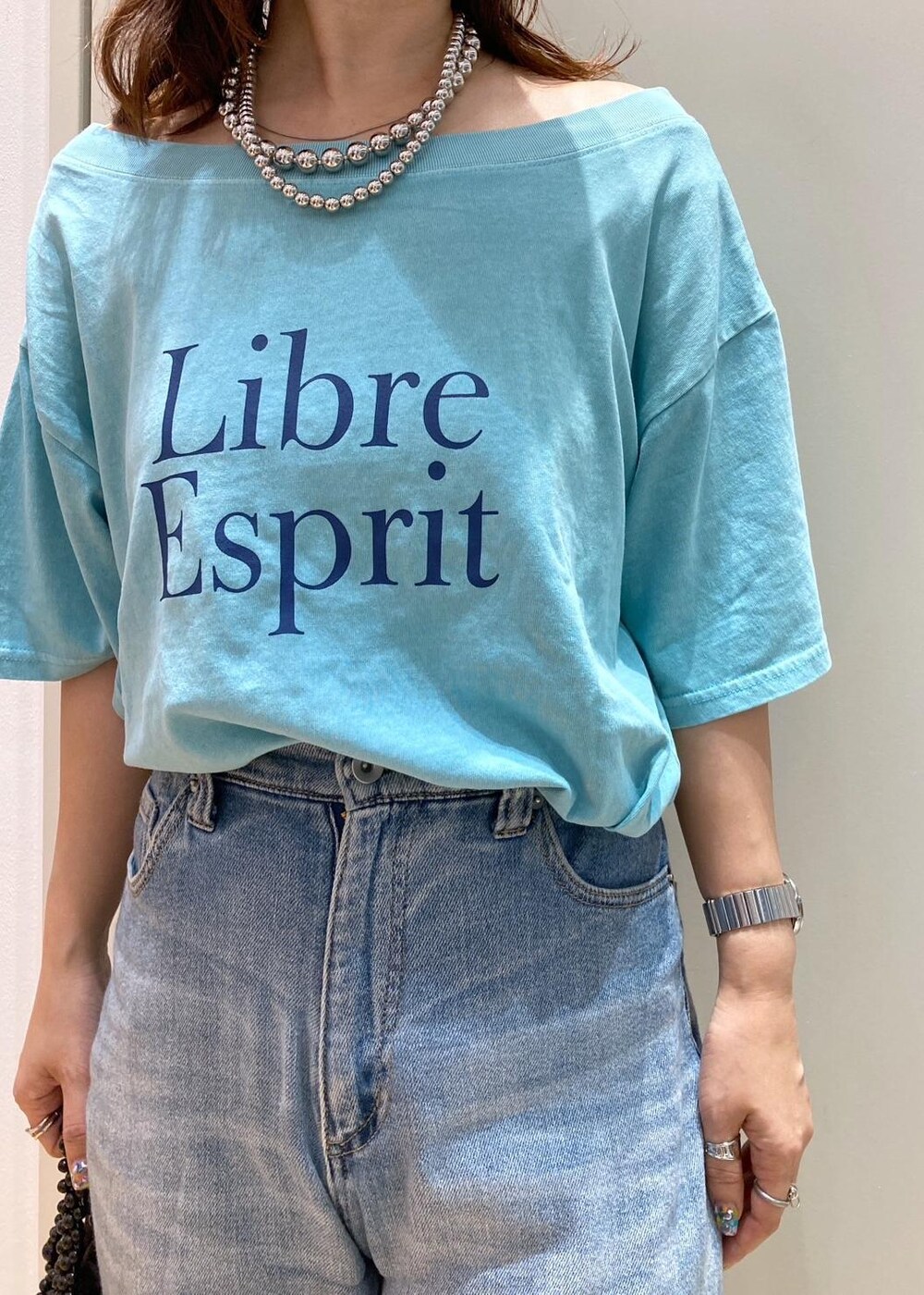 ブラック系のサンダル、ブラック系のハンドバッグ、ブルー系のTシャツ/カットソーを着用したレディースの夏コーディネートの4枚目の写真