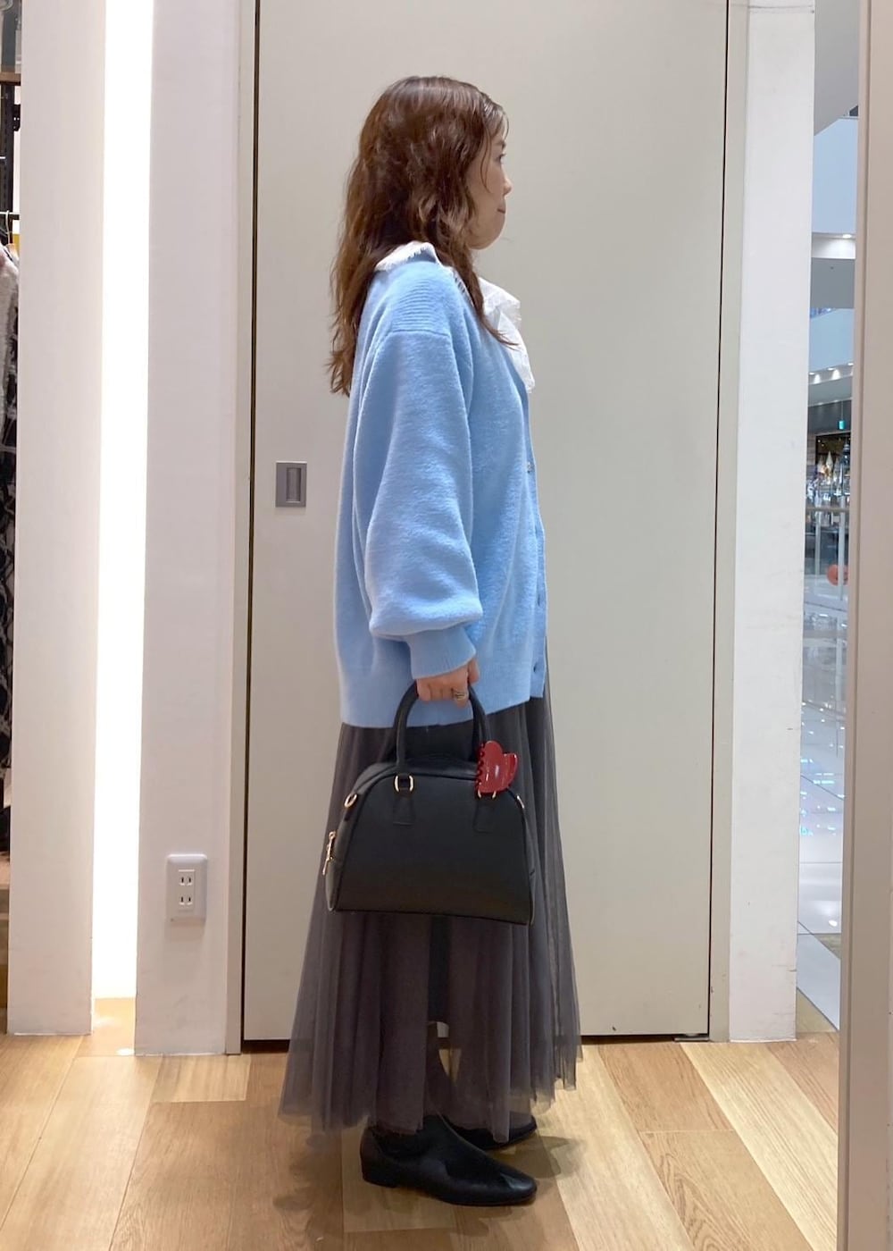 ブルー系のカーディガン/ボレロ、グレー系のスカート、ホワイト系のシャツ/ブラウスを着用したレディースの秋コーディネートの2枚目の写真