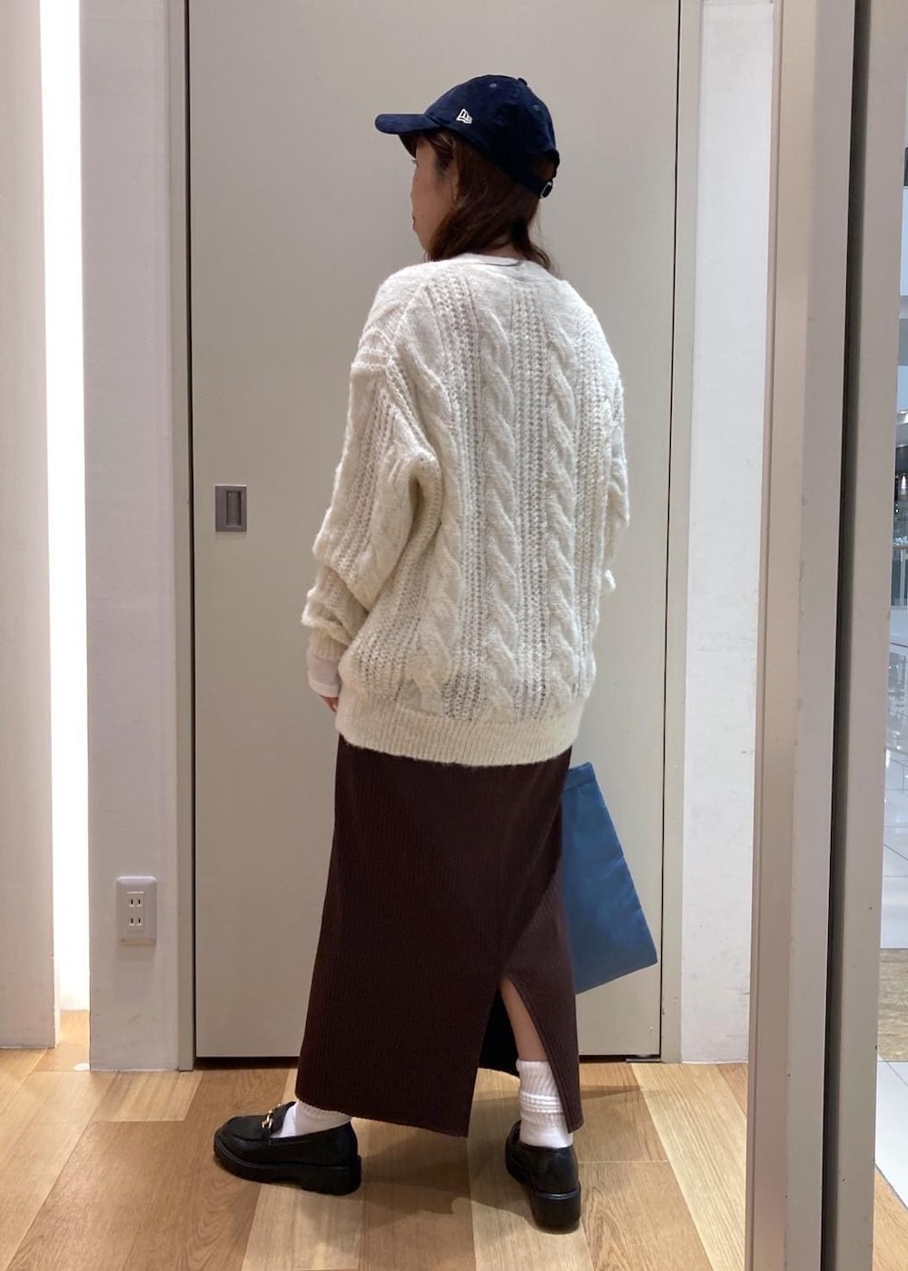 ホワイト系のTシャツ/カットソー、ブラック系のダウンジャケット/コート、ブラック系のローファーを着用したレディースの秋コーディネートの3枚目の写真