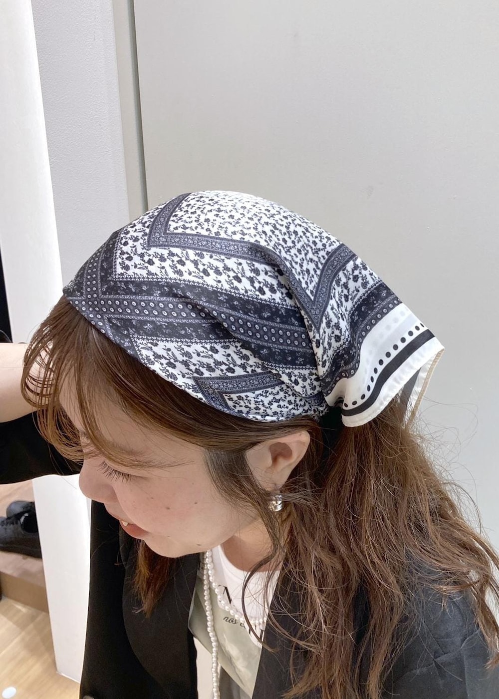 ブラック系のパンプス、ベージュ系のショルダーバッグ、ホワイト系のスカートを着用したレディースの春コーディネートの7枚目の写真