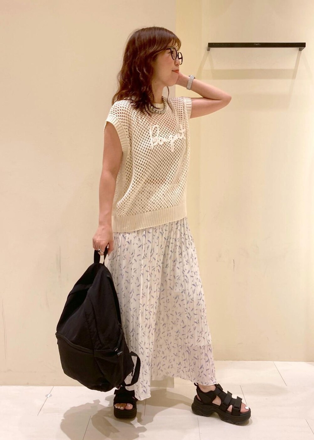 ホワイト系のニット/セーター、ホワイト系のその他パンツ、ブラック系のバックパック/リュックを着用したレディースの夏コーディネートの2枚目の写真