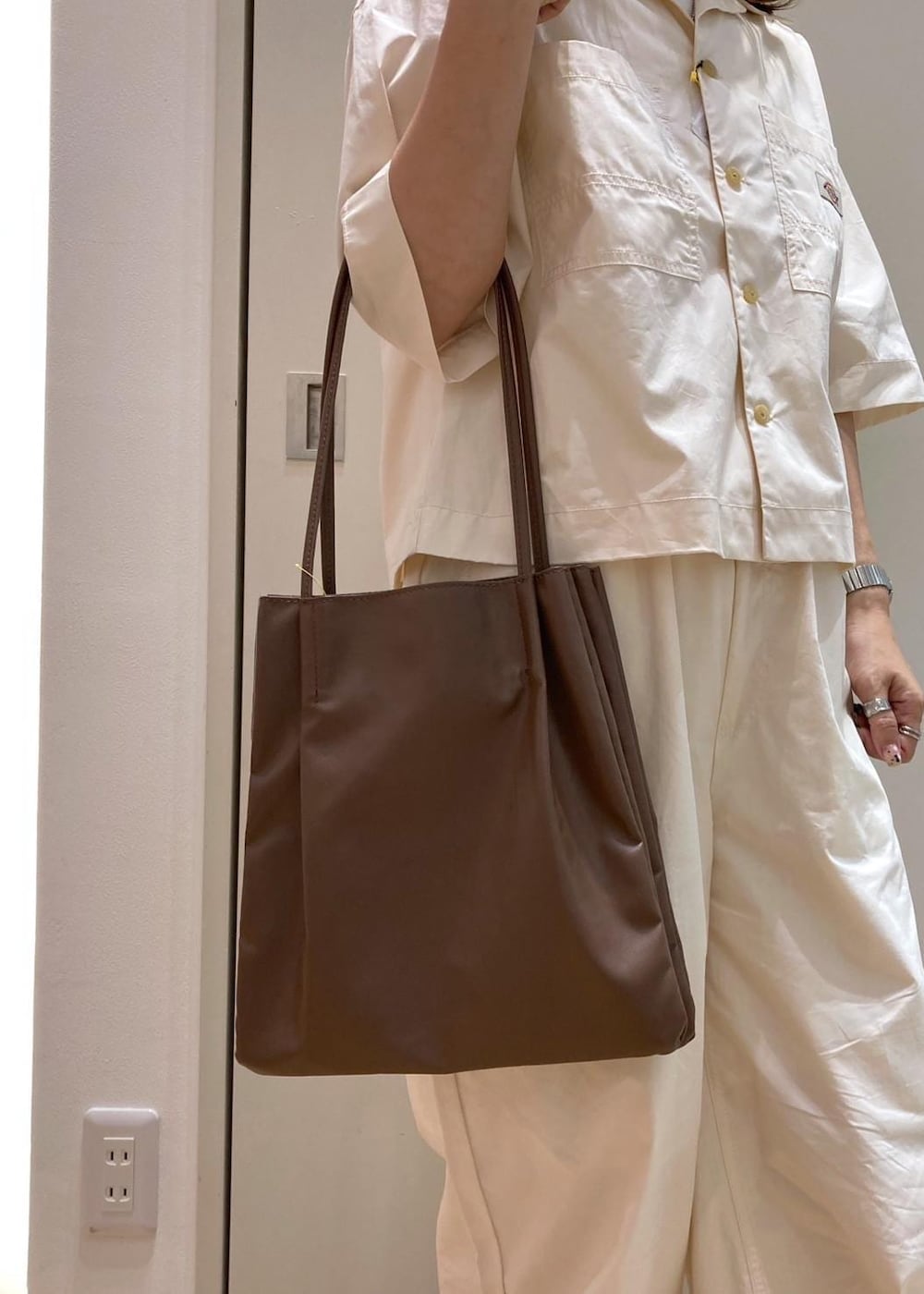 ブラウン系のトートバッグ、ブラウン系のサンダル、ホワイト系のシャツ/ブラウスを着用したレディースの夏コーディネートの9枚目の写真