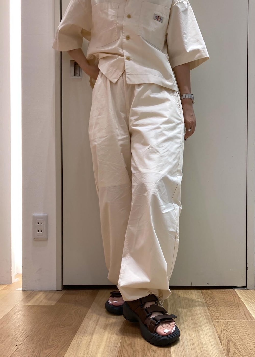 ブラウン系のトートバッグ、ブラウン系のサンダル、ホワイト系のシャツ/ブラウスを着用したレディースの夏コーディネートの7枚目の写真