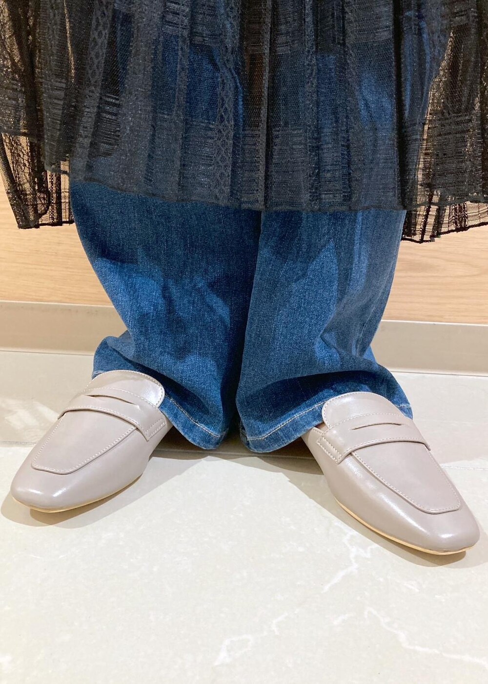 ブルー系のデニムパンツ、ブラック系のスカート、ブラック系のトートバッグを着用したレディースの春コーディネートの6枚目の写真