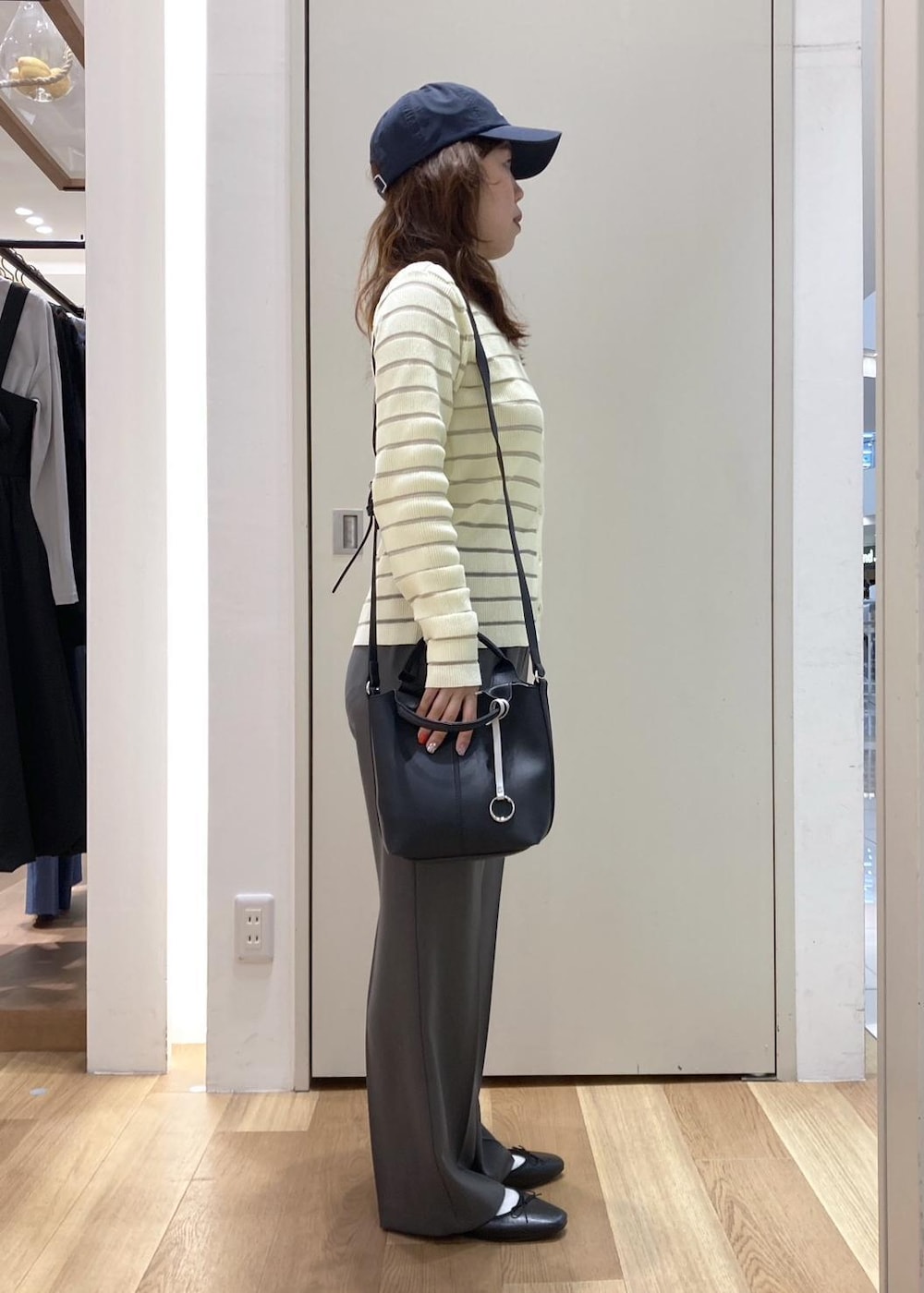 グレー系のスラックス、ベージュ系のカーディガン/ボレロ、ブラック系のバレエシューズを着用したレディースの春コーディネートの2枚目の写真