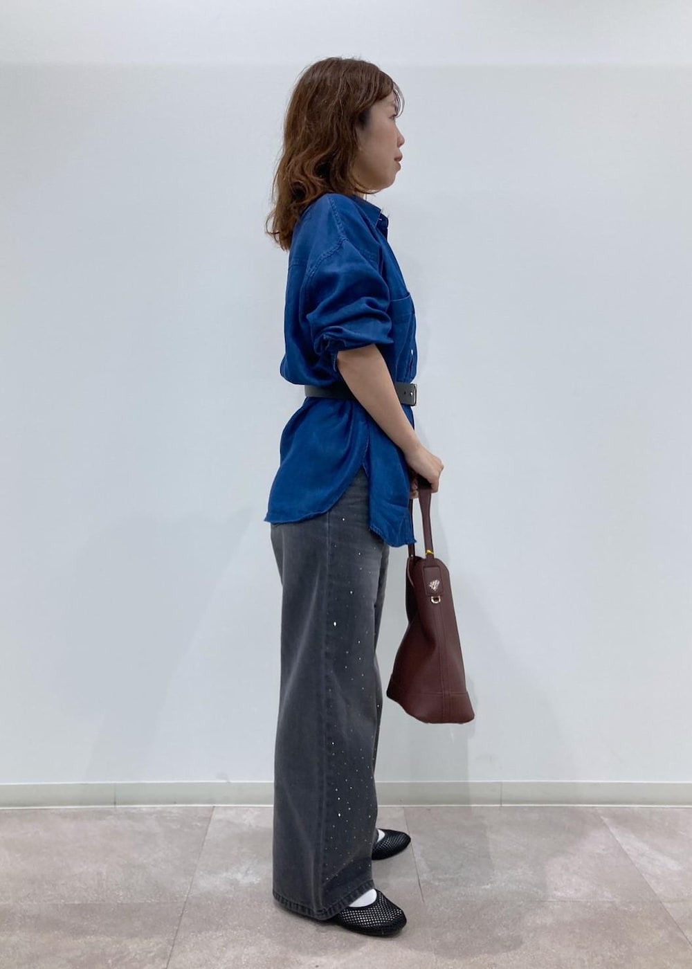 レッド系のショルダーバッグ、ブルー系のシャツ/ブラウス、ブラック系のデニムパンツを着用したレディースの夏コーディネートの2枚目の写真