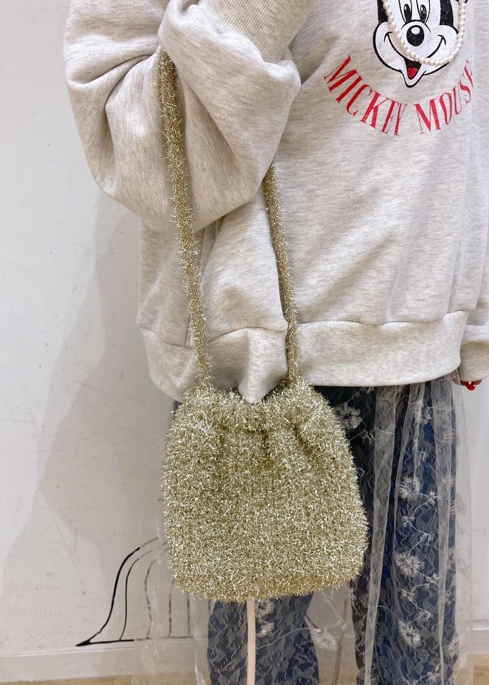 ブルー系のデニムパンツ、ホワイト系のスカート、ゴールド系のショルダーバッグを着用したレディースの秋コーディネートの10枚目の写真