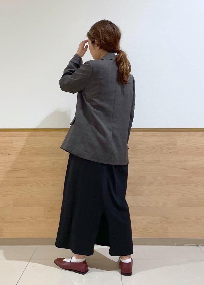 ブラウン系のテーラードジャケット、ブラック系のハンドバッグ、ブラック系のワンピースを着用したレディースの秋コーディネートの3枚目の写真