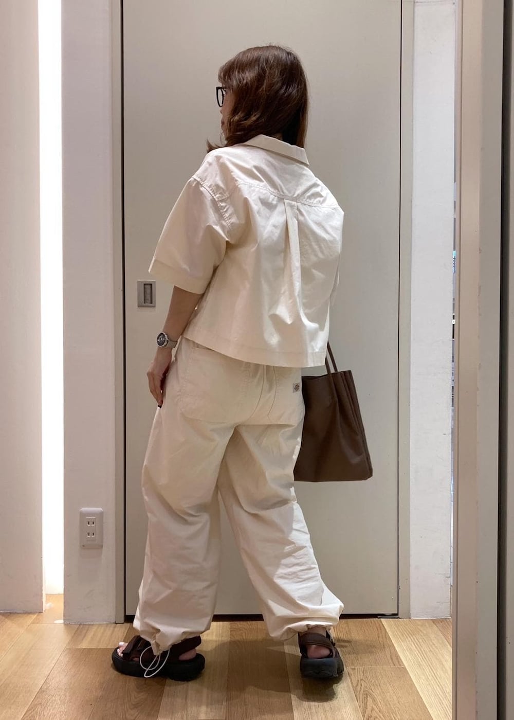 ブラウン系のトートバッグ、ブラウン系のサンダル、ホワイト系のシャツ/ブラウスを着用したレディースの夏コーディネートの4枚目の写真