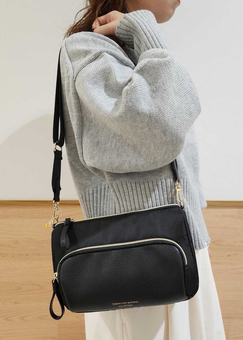 グレー系のニット/セーター、ブラック系のショルダーバッグ、ホワイト系のTシャツ/カットソーを着用したレディースの秋コーディネートの4枚目の写真