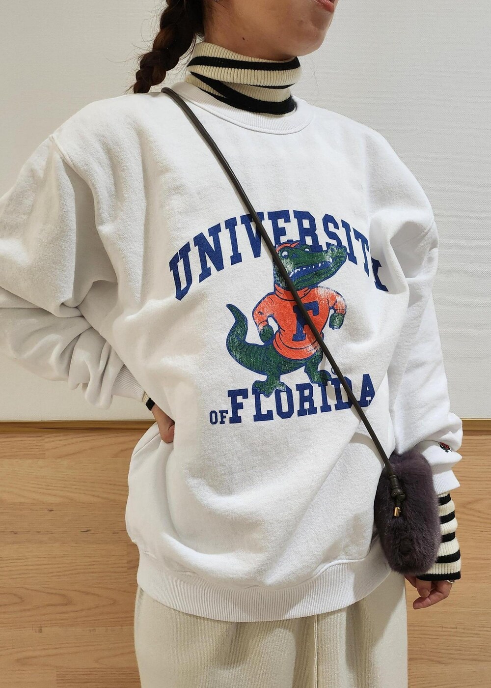 ホワイト系のジャンパースカート、ホワイト系のニット/セーター、グレー系のショルダーバッグを着用したレディースの秋コーディネートの2枚目の写真