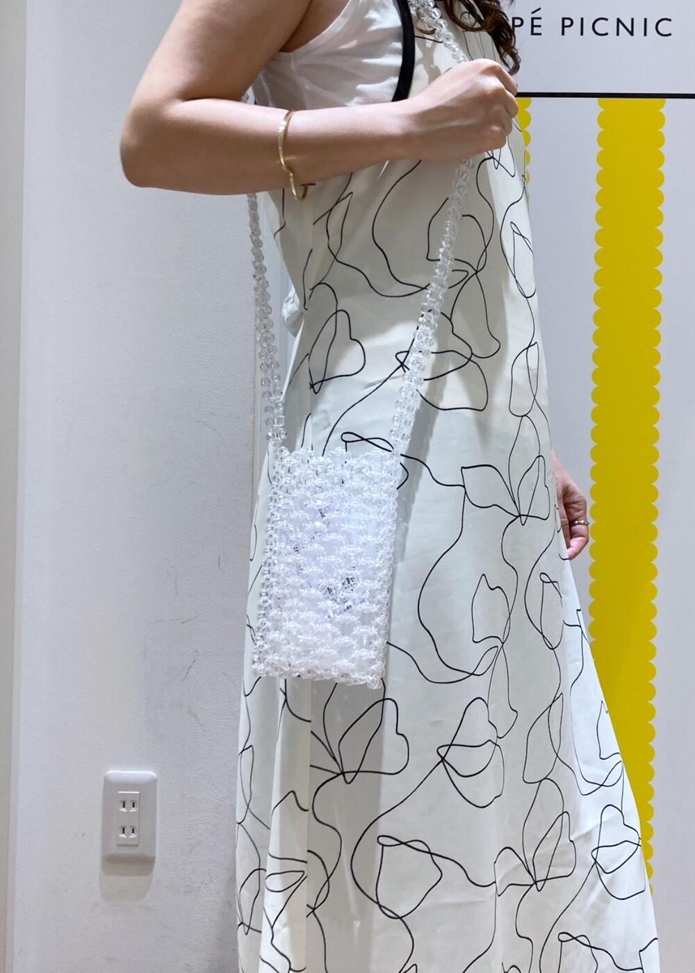 ホワイト系のワンピース、ベージュ系のTシャツ/カットソー、ブラック系のサンダルを着用したレディースの春コーディネートの3枚目の写真