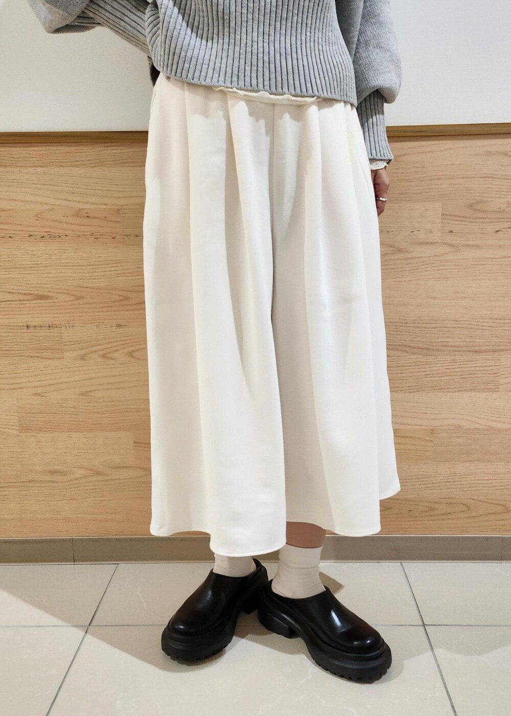 グレー系のニット/セーター、ブラック系のショルダーバッグ、ホワイト系のTシャツ/カットソーを着用したレディースの秋コーディネートの3枚目の写真