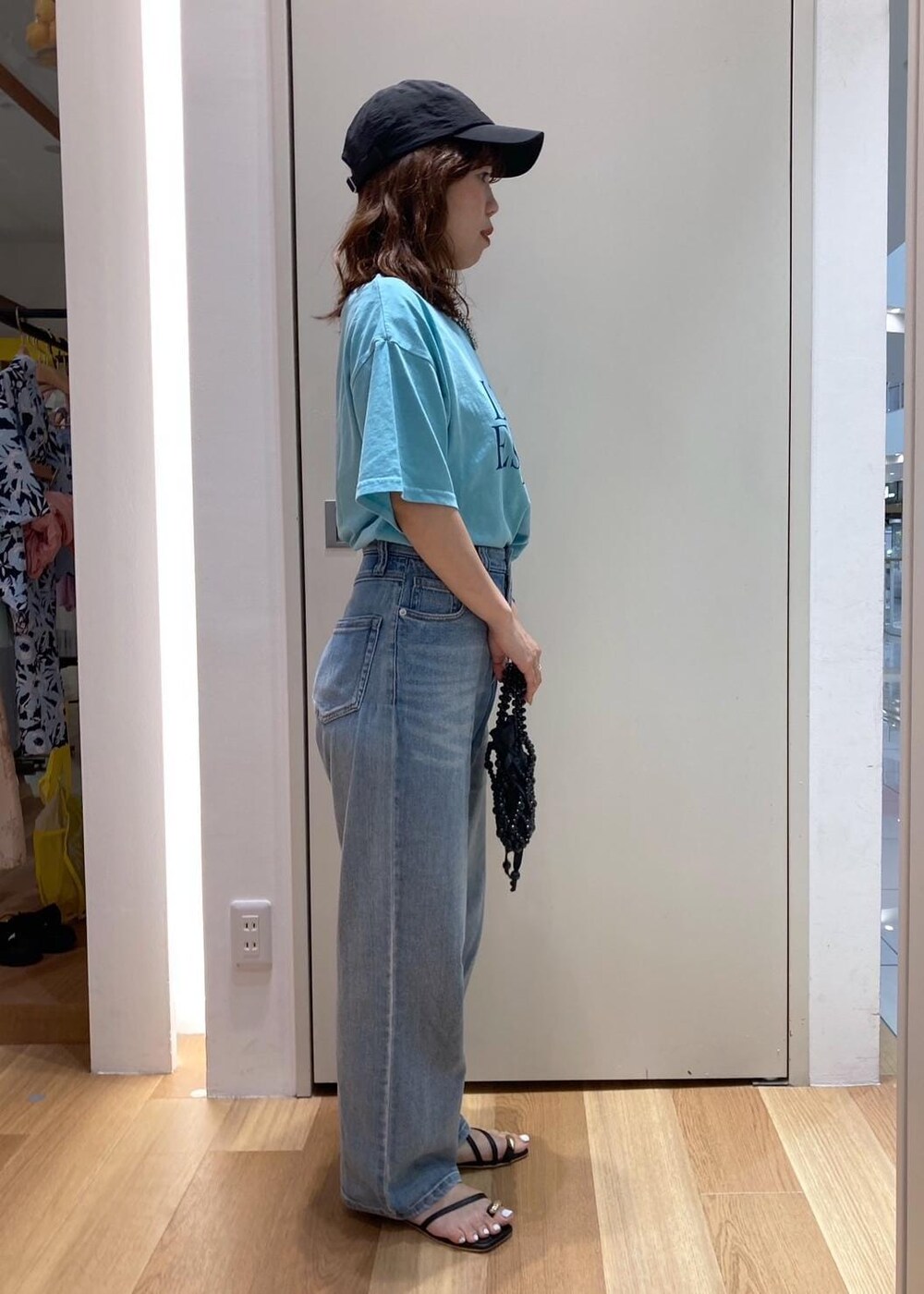 ブラック系のサンダル、ブラック系のハンドバッグ、ブルー系のTシャツ/カットソーを着用したレディースの夏コーディネートの2枚目の写真