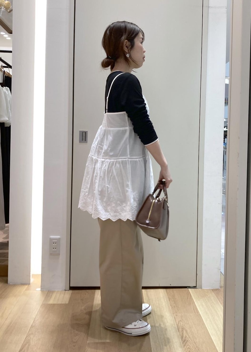 ホワイト系のキャミソール、ベージュ系のチノパンツ、ブラウン系のボストンバッグを着用したレディースの冬コーディネートの2枚目の写真