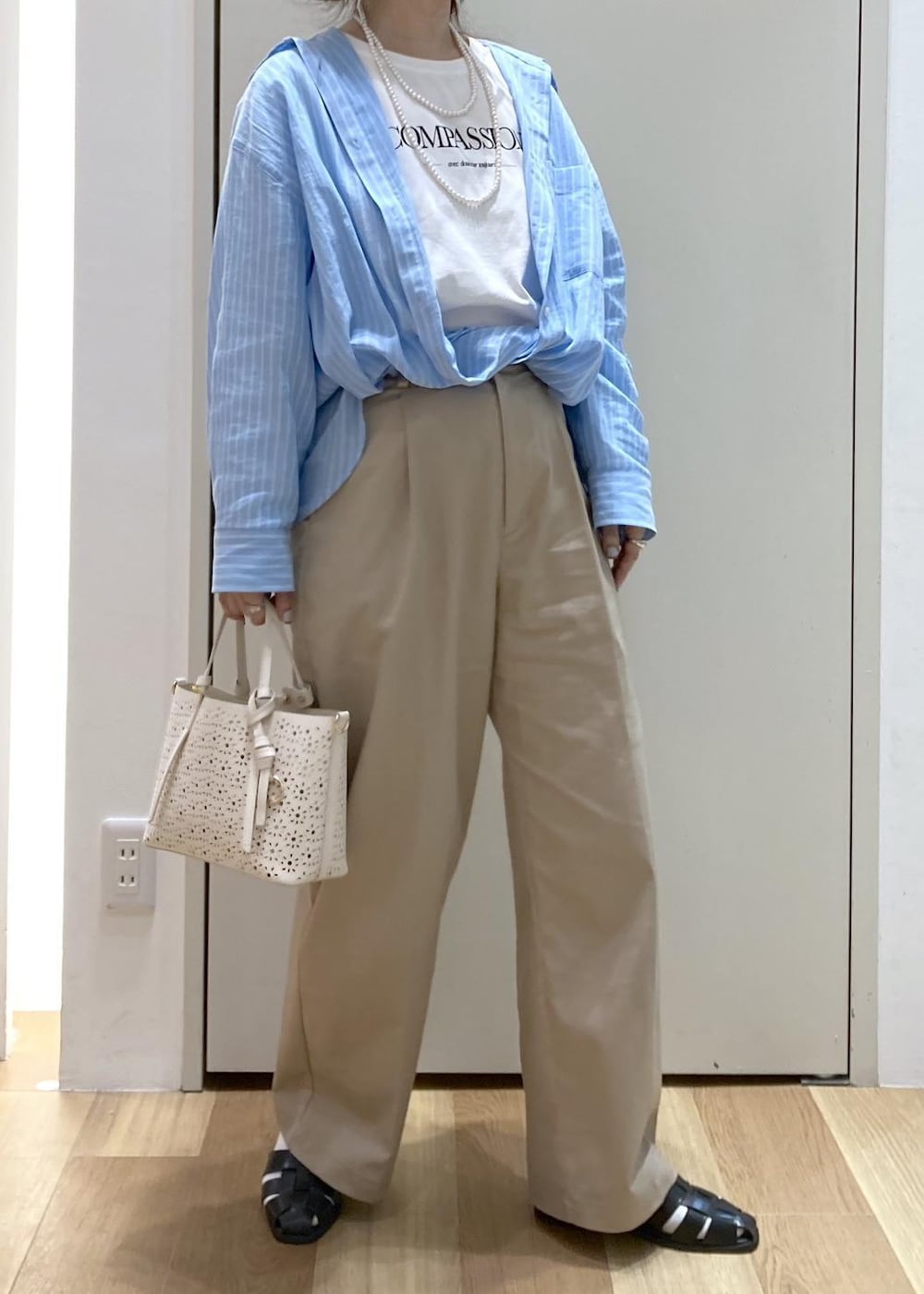 ベージュ系のチノパンツ、ブラック系のサンダル、ホワイト系のショルダーバッグを着用したレディースの春コーディネートの6枚目の写真