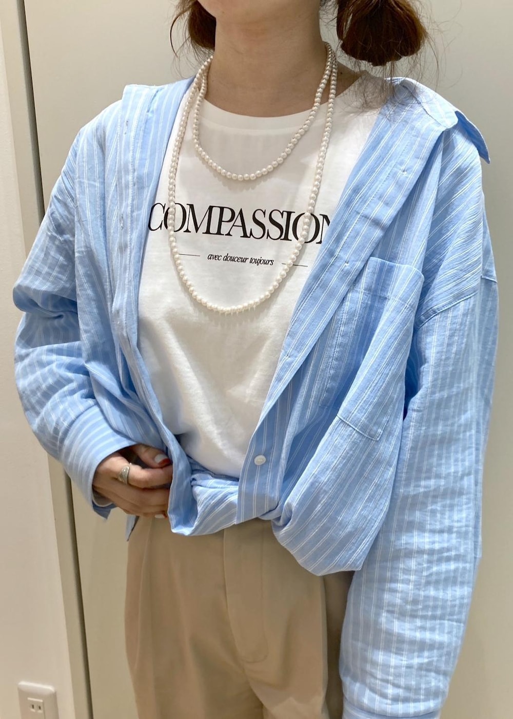 ベージュ系のチノパンツ、ブラック系のサンダル、ホワイト系のショルダーバッグを着用したレディースの春コーディネートの4枚目の写真