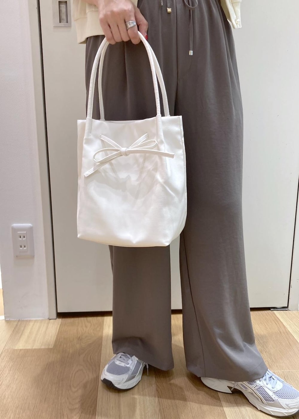 ホワイト系のトートバッグ、ホワイト系のニット/セーター、ベージュ系のTシャツ/カットソーを着用したレディースの夏コーディネートの7枚目の写真