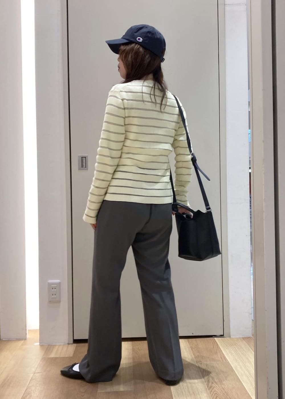 グレー系のスラックス、ベージュ系のカーディガン/ボレロ、ブラック系のバレエシューズを着用したレディースの春コーディネートの3枚目の写真