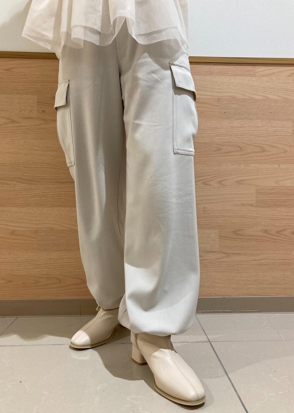 レッド系のショルダーバッグ、ホワイト系のブーツ、ホワイト系のベストを着用したレディースの冬コーディネートの4枚目の写真