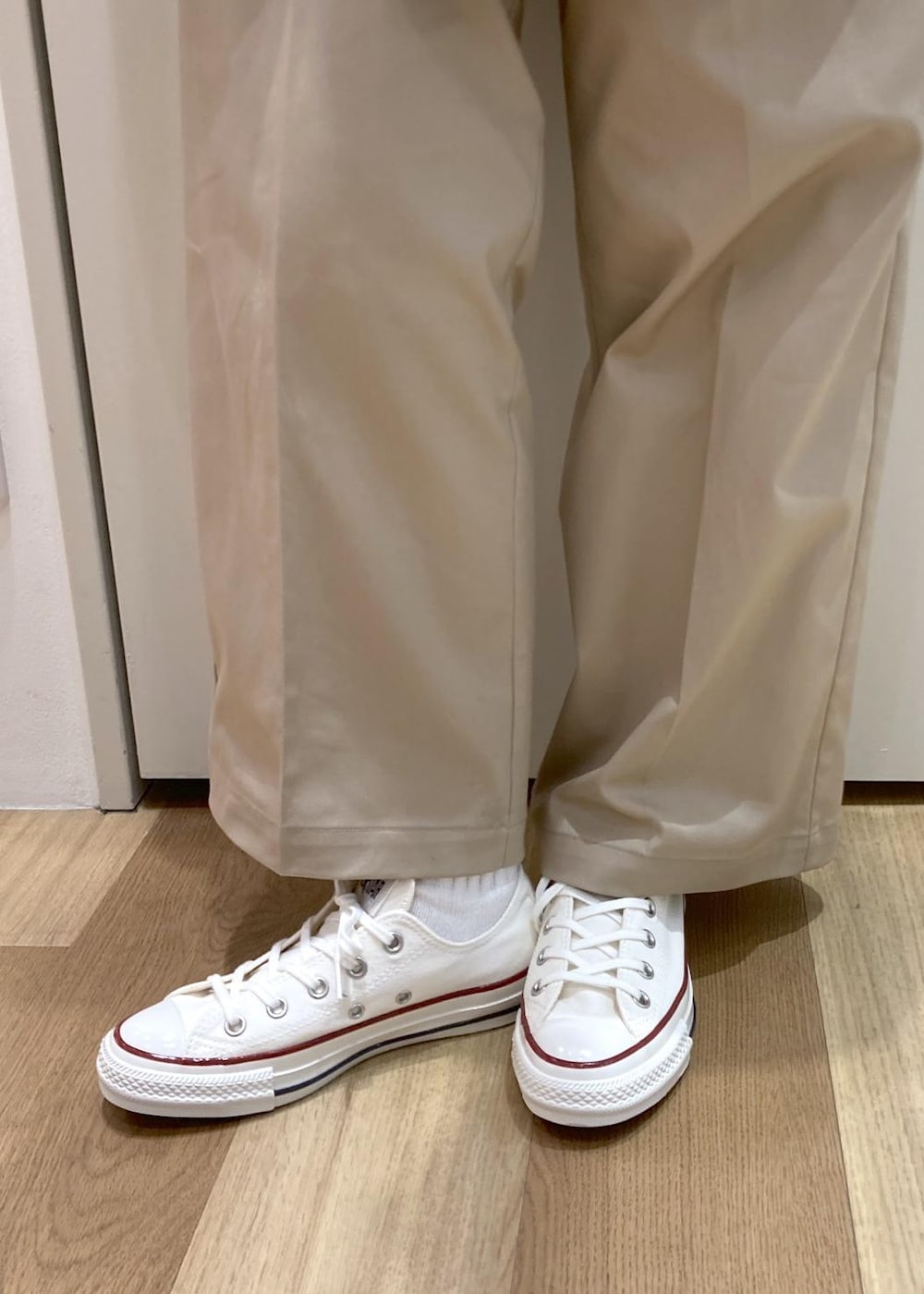 ホワイト系のキャミソール、ベージュ系のチノパンツ、ブラウン系のボストンバッグを着用したレディースの冬コーディネートの6枚目の写真