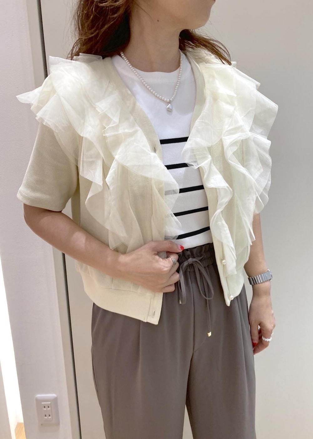 ホワイト系のトートバッグ、ホワイト系のニット/セーター、ベージュ系のTシャツ/カットソーを着用したレディースの夏コーディネートの4枚目の写真