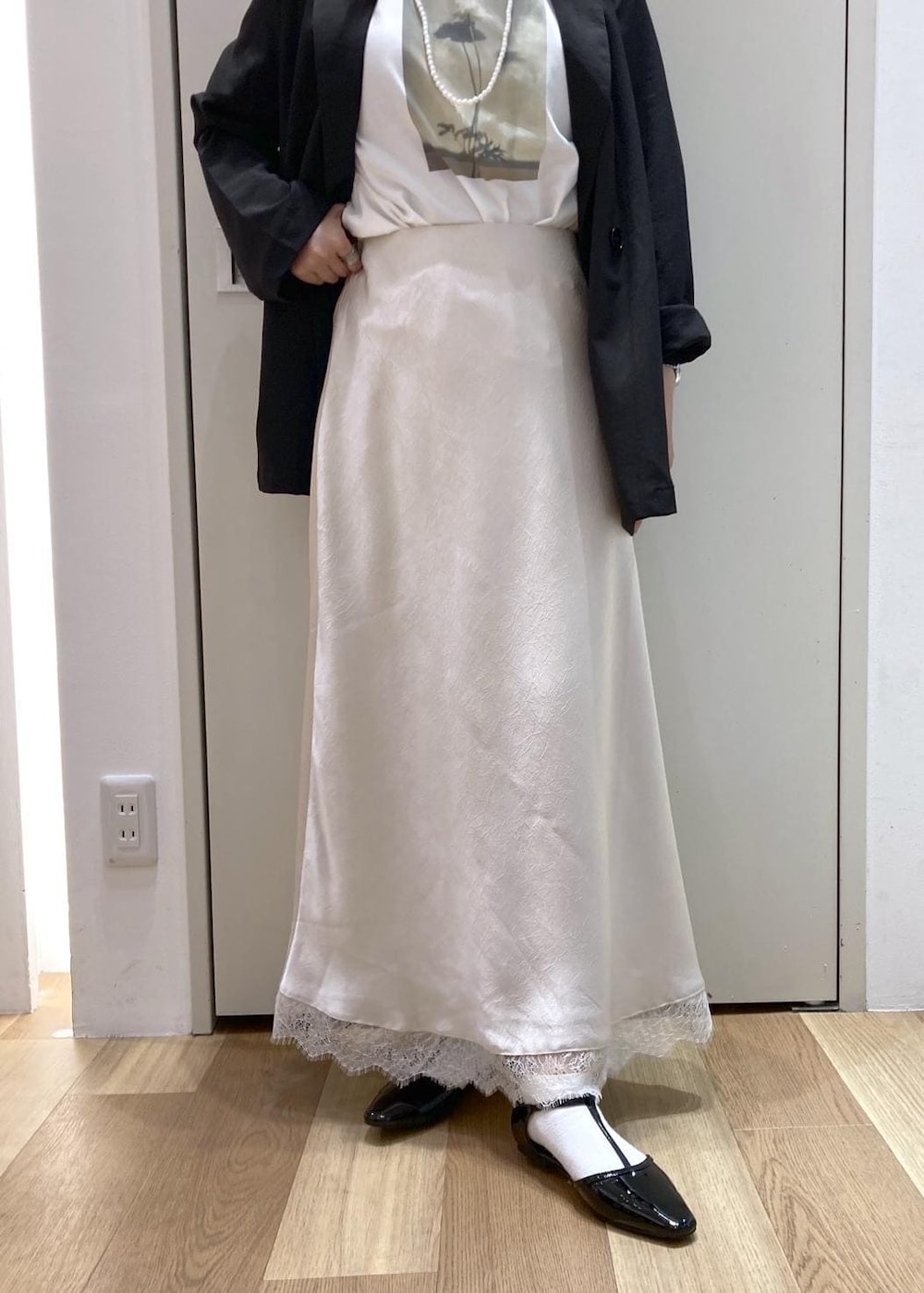ブラック系のパンプス、ベージュ系のショルダーバッグ、ホワイト系のスカートを着用したレディースの春コーディネートの5枚目の写真