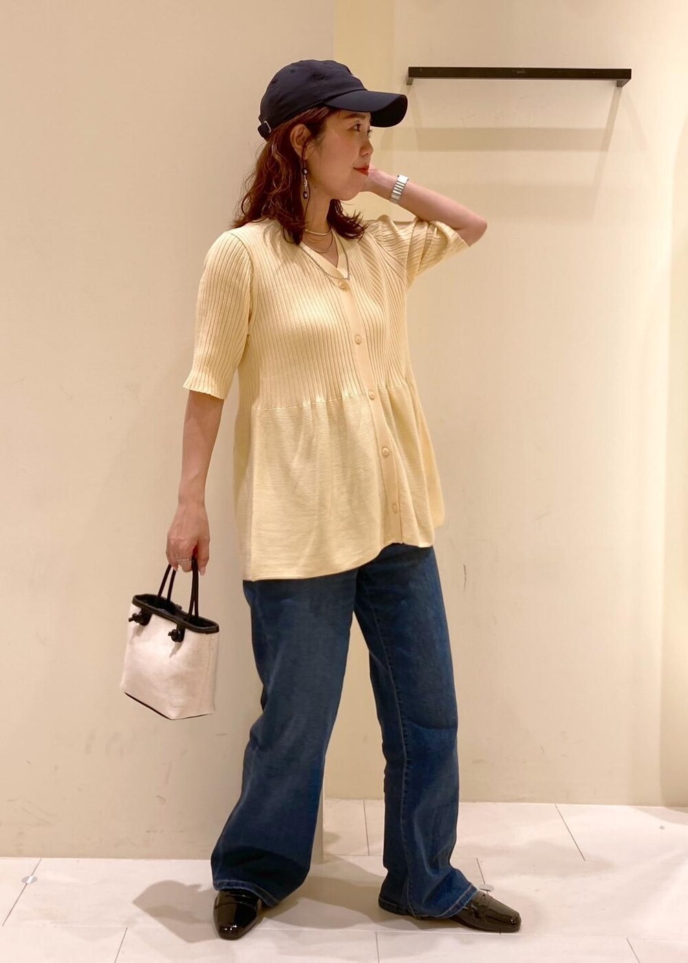 ブルー系のデニムパンツ、ブラック系のトートバッグ、ベージュ系のカーディガン/ボレロを着用したレディースの夏コーディネートの2枚目の写真