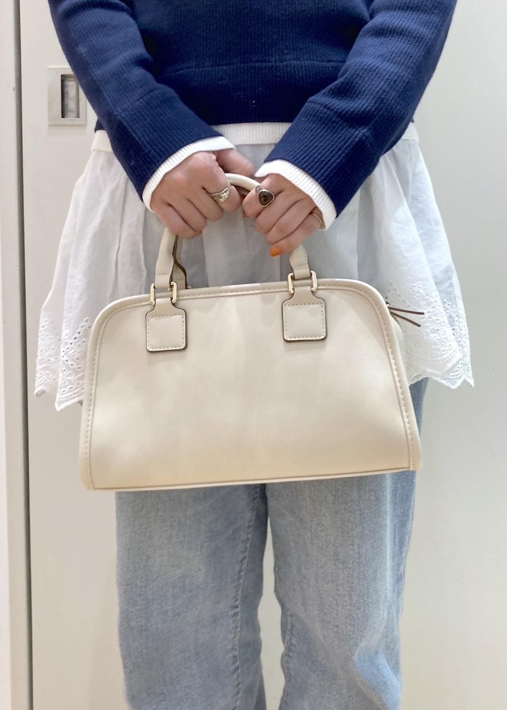 ブルー系のデニムパンツ、ホワイト系のボストンバッグ、ブルー系のニット/セーターを着用したレディースの冬コーディネートの9枚目の写真