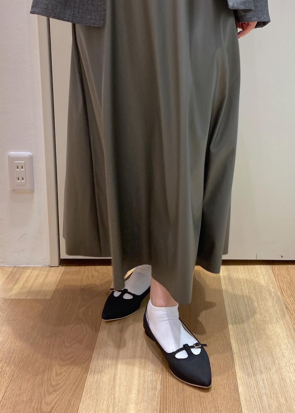 グレー系のテーラードジャケット、グリーン系のスカート、ブラック系のパンプスを着用したレディースの秋コーディネートの7枚目の写真