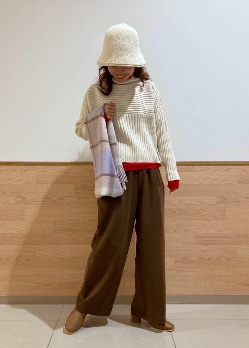 レッド系のTシャツ/カットソー、ホワイト系のニット/セーター、ブラウン系のブーツを着用したレディースの冬コーディネートの3枚目の写真