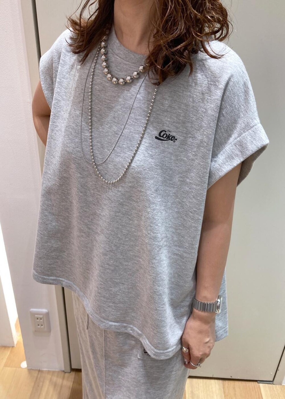 ブラック系のサンダル、レッド系のトートバッグ、グレー系のスカートを着用したレディースの夏コーディネートの4枚目の写真